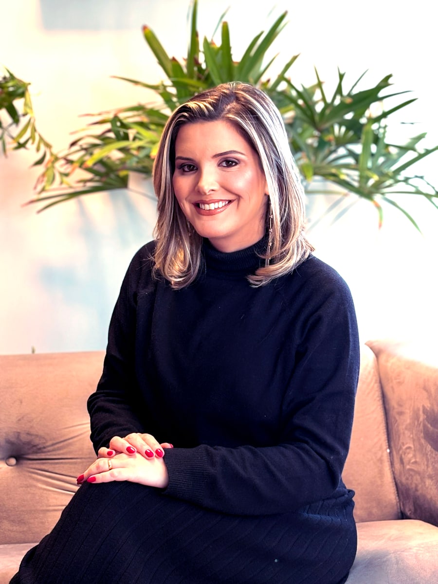 Nicole Venturin Padilha sentada, em ambiente de trabalho